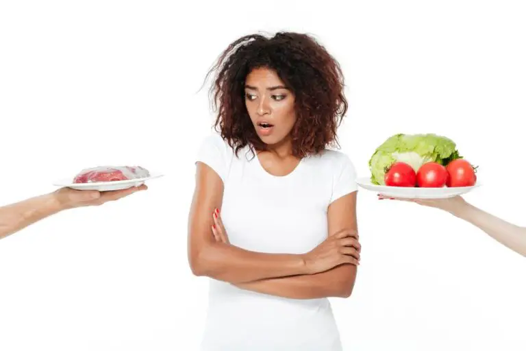 Confused young african woman choosing between meat and vegetables