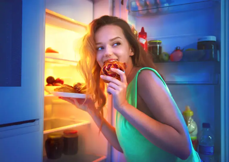Beautiful teenage girl taking food from refrigerator at night