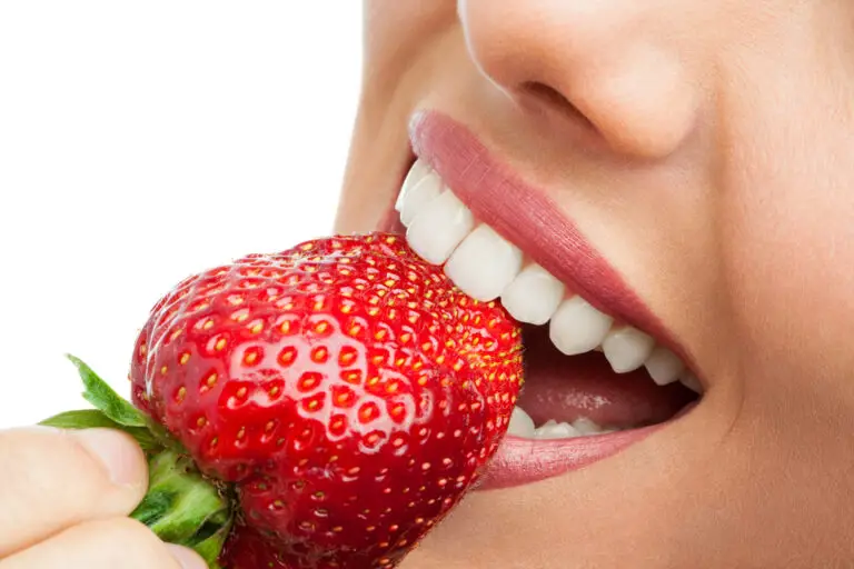Extreme close up of teeth biting strawberry