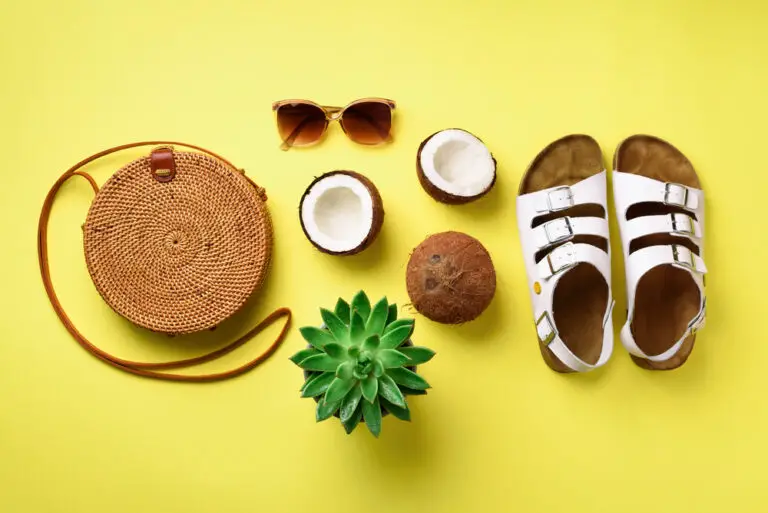 Stylish rattan bag, coconut, birkenstocks, palm branches, succulent, sunglasses on yellow background. Banner. Top view with copy space. Trendy bamboo bag and white shoes