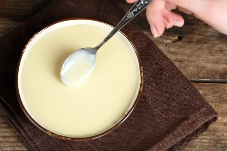 Bowl with condensed milk and spoon on table close up