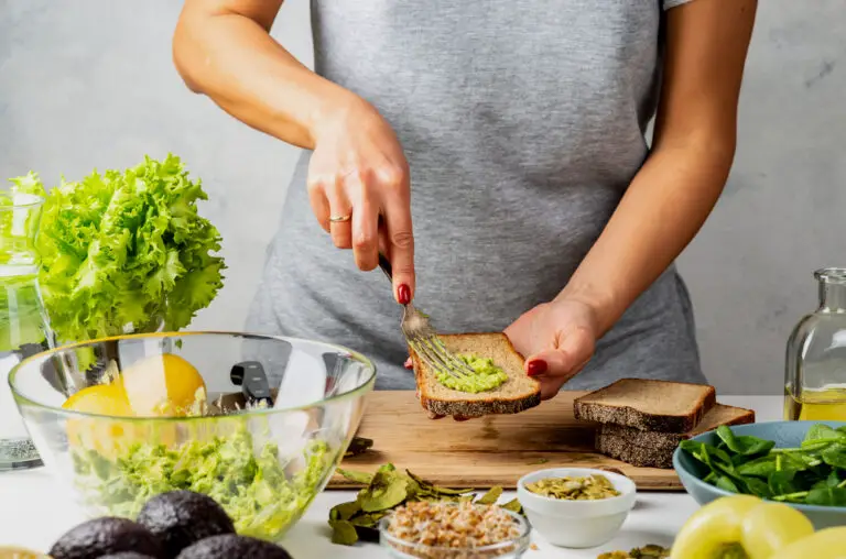 Woman spreads avocado guacamole on bread. healthy food concept
