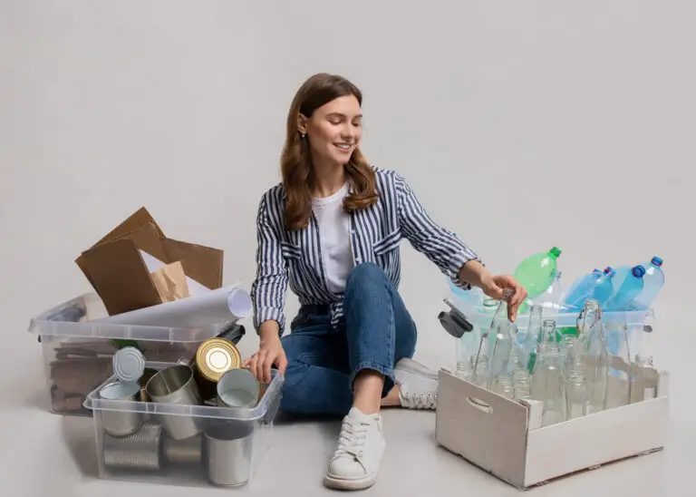 Portrait Of Young Woman Sitting Among Containers With Sorted Garbage