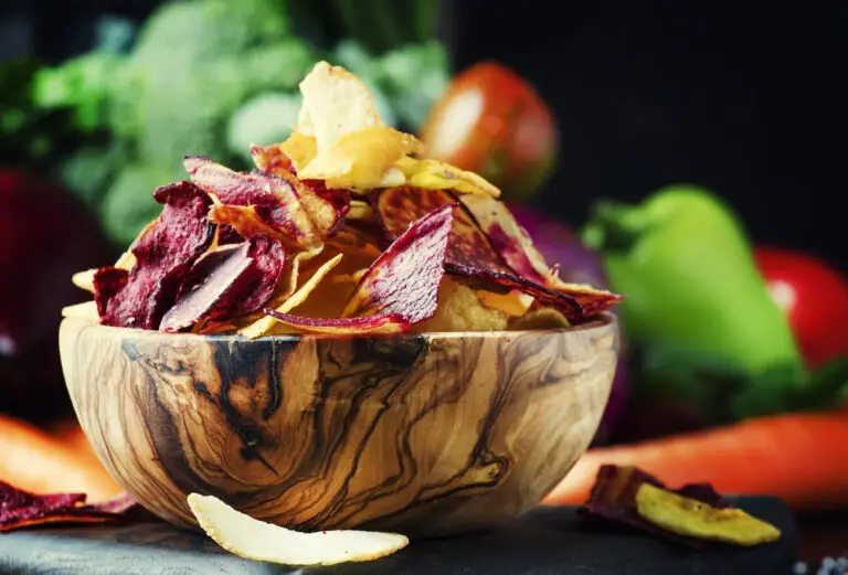 Vegan snacks, multicolored vegetable chips in  wooden bowl, back