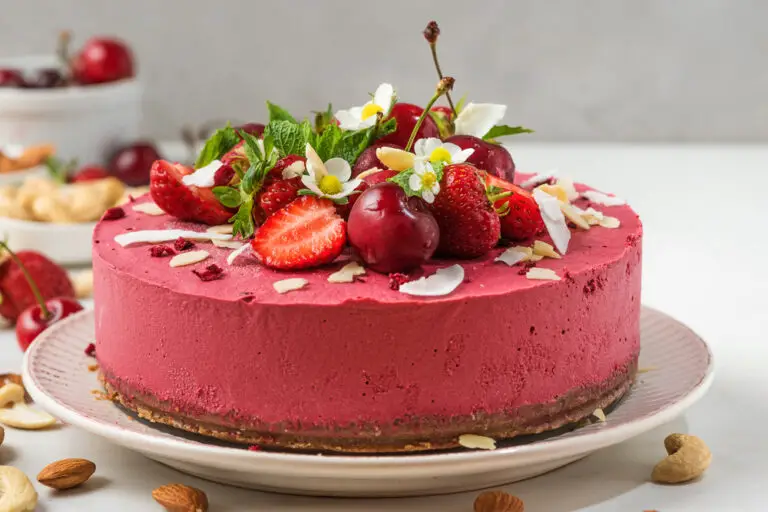 raw vegan berry cheesecake made of cashew, cherry, strawberries, coconut, almonds and dates with fresh berries